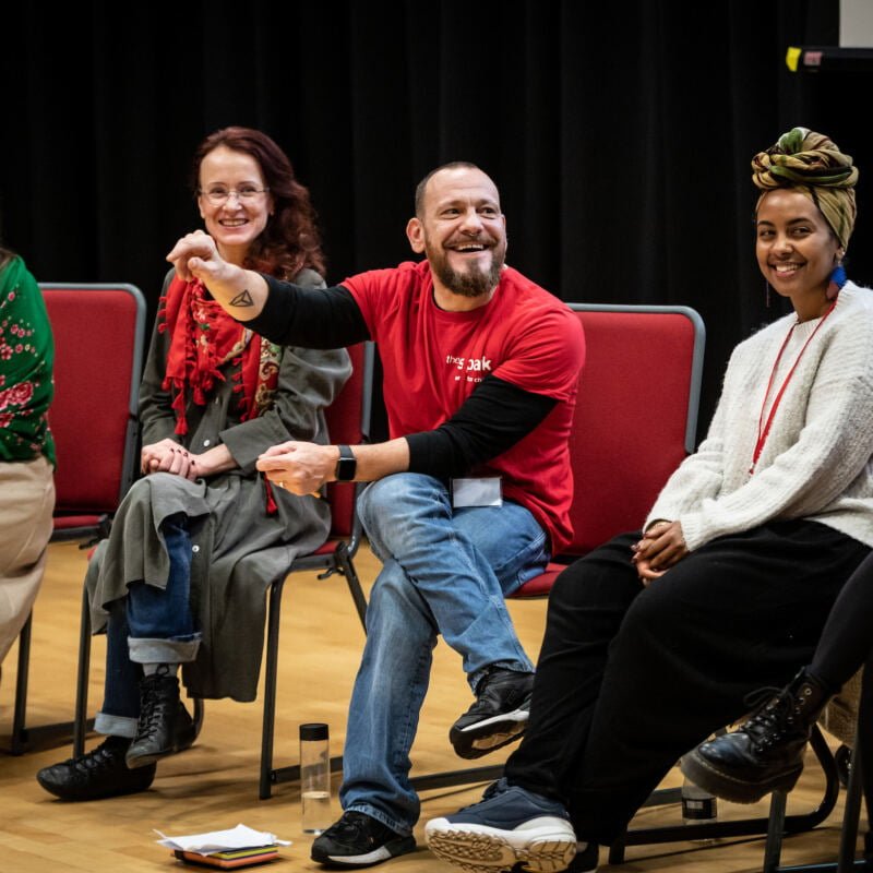 A row people sit in a panel discussion, laughing