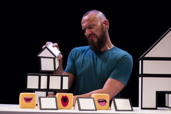 A performers plays with blocks resembling houses.