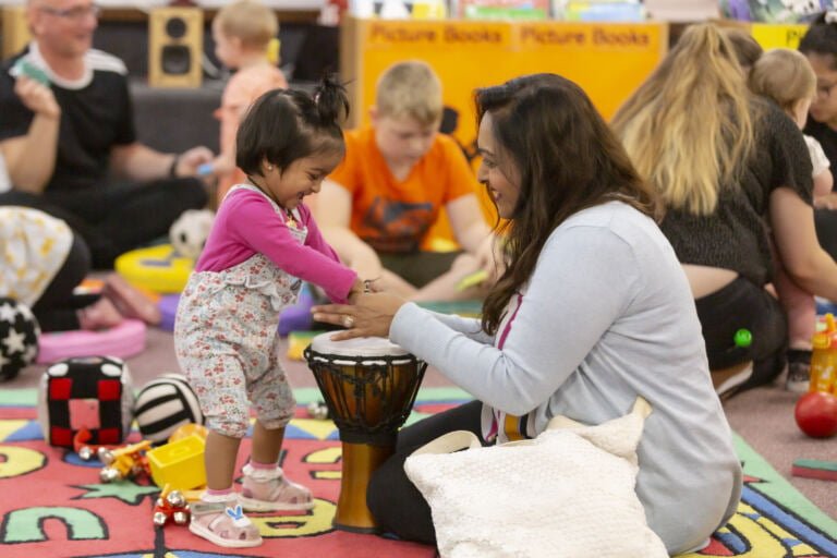A parent and their toddler drum together