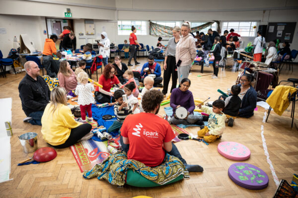 Children and their families playing with instruments on the floor.