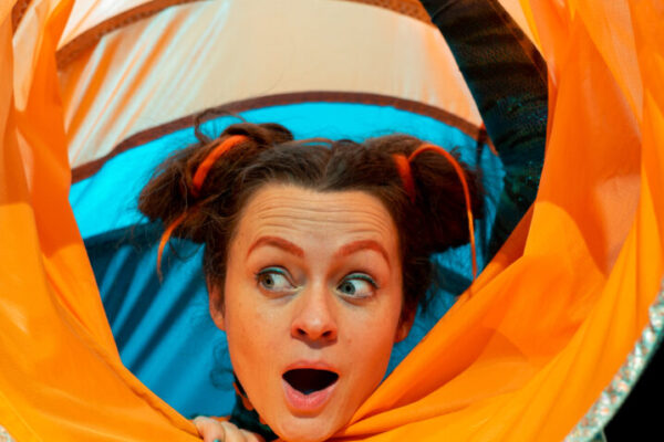 A lady in a blue and orange tube with a playful expression on her face.